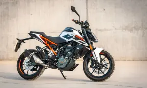 En vit och orange KTM 125 Duke redo för fart. Denna lätta motorcykel är perfekt för att uppleva hastighet i stadsmiljö.