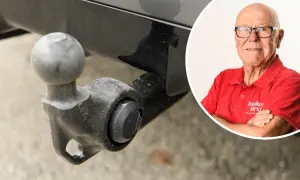 En man i röd tröja från "Tekniker Värld" ler bredvid en avtagbar dragkrok. Viktigt för besiktning.
