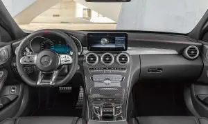 Mercedes C-Klass interior dashboard with steering wheel, infotainment screen, and carbon fiber accents.
