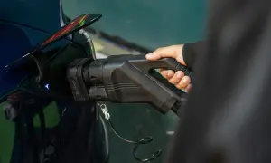 En hand håller i en laddningskabel för en elbil. Snabb laddning elbil pris är en viktig faktor för många.