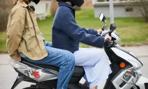 Två personer på moped, en bakom den andra. Följer 30 moped regler för en säker tur.