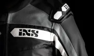 Detaljer på en svart och grå ixs motorcykeljacka med vita logotyper.