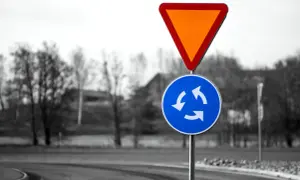 Varningsskylt för cirkulationsplats och väjningsplikt. Viktiga trafikregler frågor för säker körning.