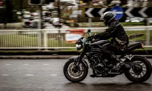 Motorcyklist i full fart på en svart motorcykel, med en praktisk tubhalsduk runt halsen för att skydda mot vinden.