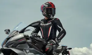 Förare i ett svart och rött skinnställ sitter på en motorcykel.