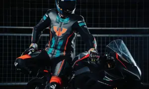 Förare i en färgglad läderdräkt sitter på en svart motorcykel.