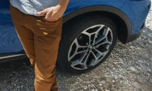 Man med bruna byxor vid en blå Renault Kadjar. Ett hjul syns tydligt, kanske ett tecken på ett Renault Kadjar problem?