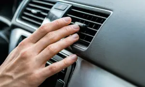 Hand justerar luftkonditionering bil för behaglig temperatur.
