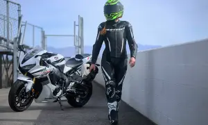 En förare i skinnställ går bredvid en vit Honda. Skinnställ storleksguide hjälper dig hitta rätt passform för din körning.