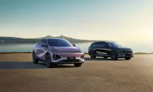 Två XPeng SUV:ar, en lila och en svart, står vid en sjö med berg i bakgrunden.