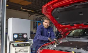 Mekaniker arbetar med bilens AC-system. En maskin med tryckmätare visar hur fungerar ac i bilen.