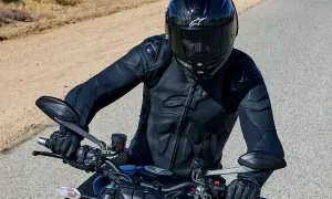 Motorcyklist i en Alpinestars skinnjacka, redo för äventyr på en öppen väg.