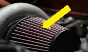 En gul pil pekar på det röda luftfiltermaterialet på ett bilfilter.