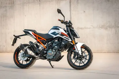 En vit och orange KTM 125 Duke redo för fart. Denna lätta motorcykel är perfekt för att uppleva hastighet i stadsmiljö.