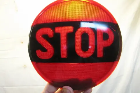 Rött stoppskylt med texten "STOP" i svarta bokstäver. En klassisk olja symbol för att stanna.