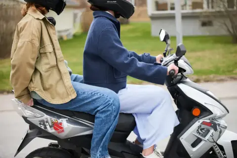 Två personer på moped, en bakom den andra. Följer 30 moped regler för en säker tur.