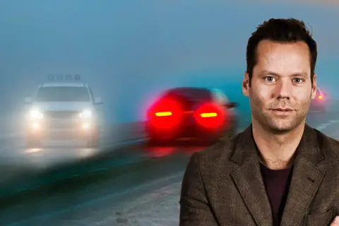 Man i kostym framför dimmig väg med bilar. Viktigt med dimljus regler för säkerhet.