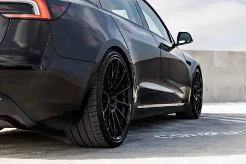 Svart Tesla Model 3 med blanka fälgar, redo för service.
