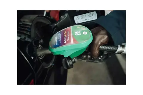 En hand i brun handske håller i en bensinpump med texten "GoEasyExtra 98 Bensin E5". Bredvid syns en etikett med "95".