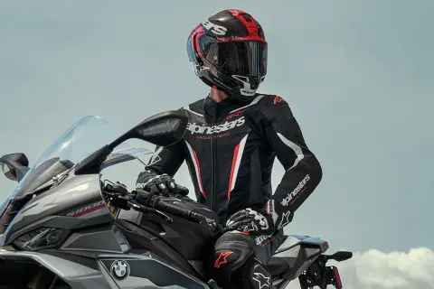 Förare i ett svart och rött skinnställ sitter på en motorcykel.