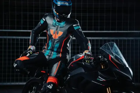 Förare i en färgglad läderdräkt sitter på en svart motorcykel.