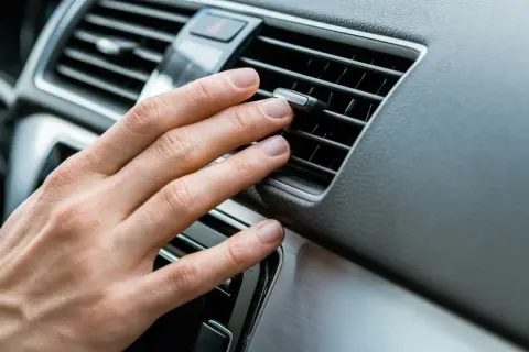 Hand justerar luftkonditionering bil för behaglig temperatur.