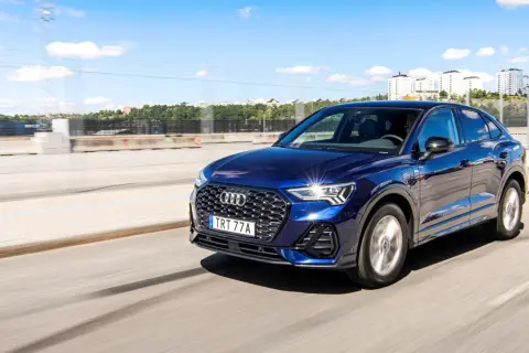 Mörkblå Audi Q3 kör på en motorväg i Sverige. Inga problem med denna bil, bara en härlig dag.