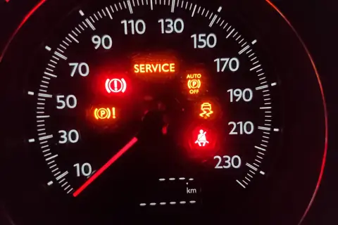 Car dashboard with multiple illuminated warning lights: SERVICE, brake, traction control, seatbelt, and auto park off.