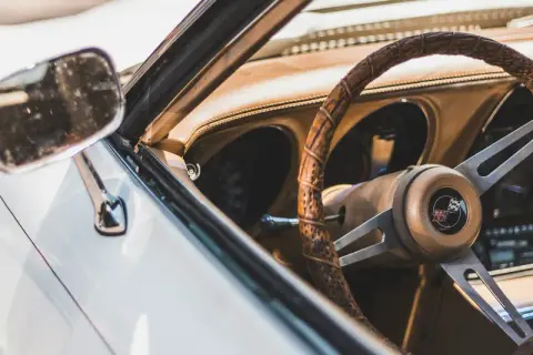 Detaljer från en vit bil, inklusive ratt och instrumentbräda. En nyckel sitter i tändningen, redo att visa hur startar man en bil.