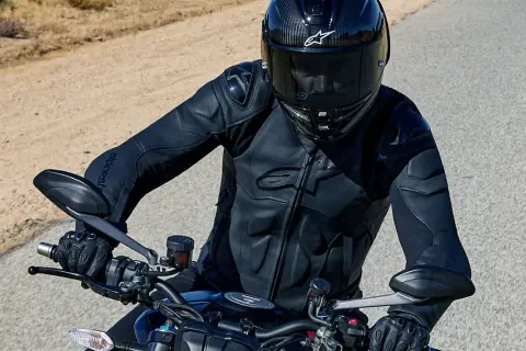 Motorcyklist i en Alpinestars skinnjacka, redo för äventyr på en öppen väg.