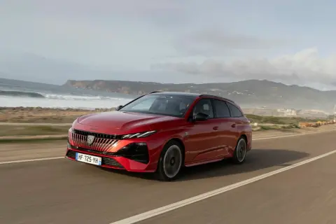 Röd Peugeot 308 kombi kör längs en kustväg. Inga problem med denna bil, bara en vacker vy.