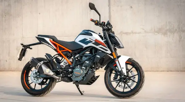 En vit och orange KTM 125 Duke redo för fart. Denna lätta motorcykel är perfekt för att uppleva hastighet i stadsmiljö.