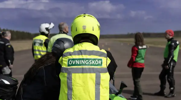 Motorcykelutbildning pågår. En handledare med texten "Övningskör" på västen står redo. Frågan om hur många elever en handledare får ha är relevant för säkerheten.