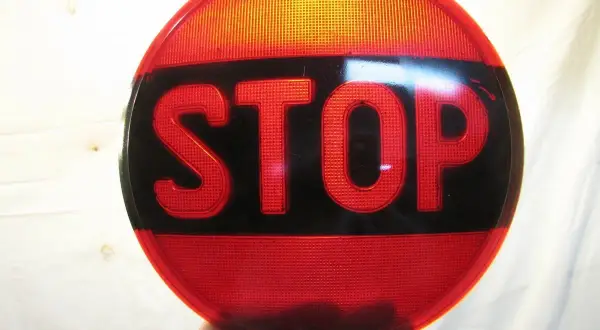 Rött stoppskylt med texten "STOP" i svarta bokstäver. En klassisk olja symbol för att stanna.