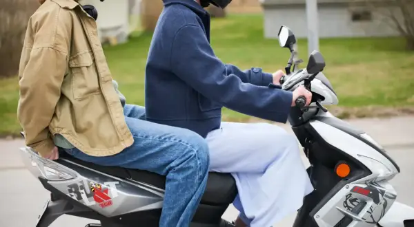 Två personer på moped, en bakom den andra. Följer 30 moped regler för en säker tur.