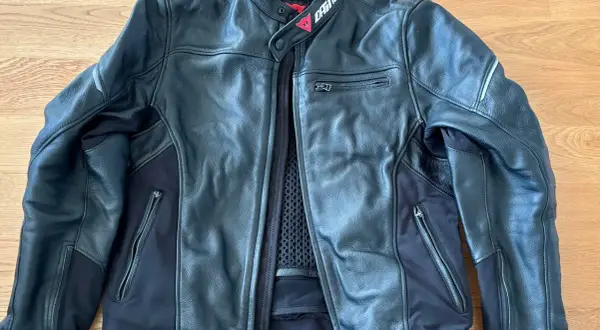 Svart Dainese skinnjacka med dragkedjor och meshfoder. Perfekt för motorcykeläventyr.