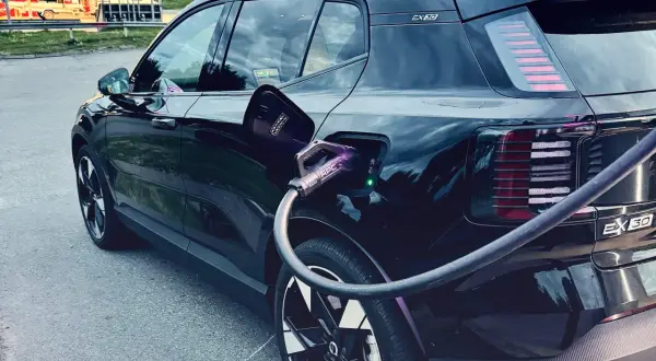 Svart elbil, troligen mest sålda elbilen, laddas vid en laddstation.