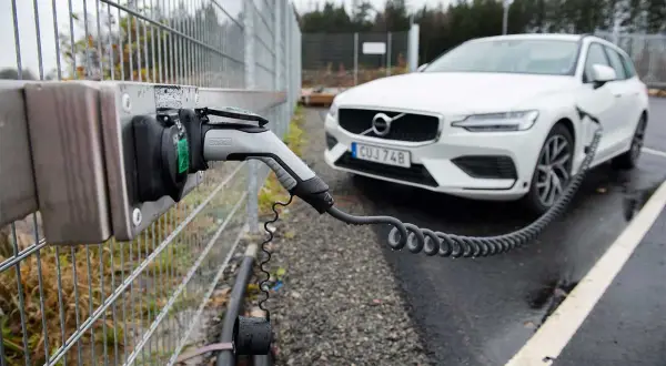 En vit Volvo laddas vid en laddstation. Perfekt för att hitta laddstationer när du är på språng.