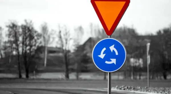 Varningsskylt för cirkulationsplats och väjningsplikt. Viktiga trafikregler frågor för säker körning.
