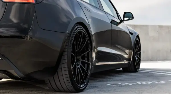 Svart Tesla Model 3 med blanka fälgar, redo för service.