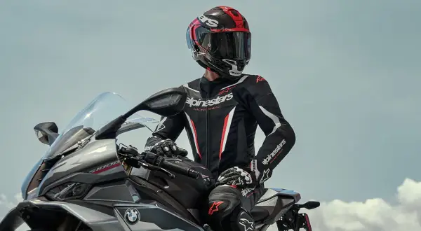 Förare i ett svart och rött skinnställ sitter på en motorcykel.