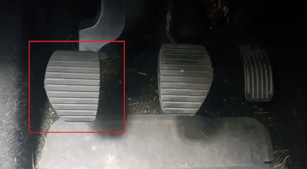 Kopplingspedalen i en manuell bil, markerad med röd ram. Denna pedal är avgörande för att växla.