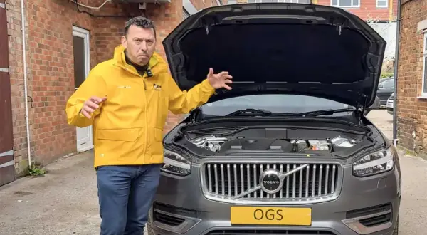 Man i gul jacka gestikulerar vid motorhuven på en Volvo XC60 som inte startar.