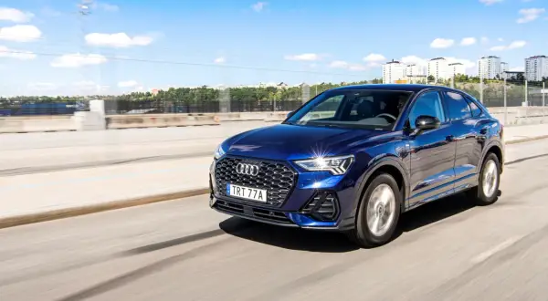 Mörkblå Audi Q3 kör på en motorväg i Sverige. Inga problem med denna bil, bara en härlig dag.