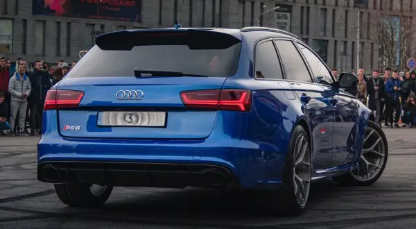 Blue Audi RS6 Avant with a crowd watching.