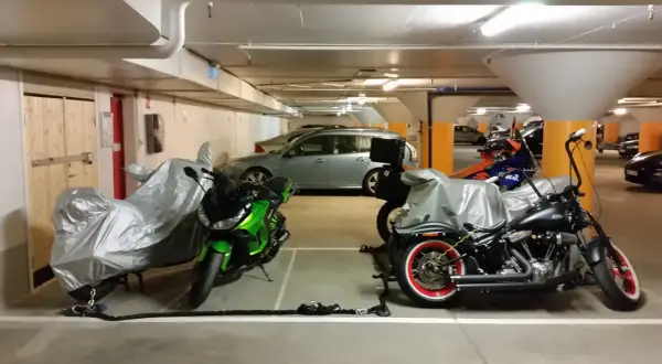 Här parkerar du moped klass 1: två motorcyklar, en grön och en svart, står i ett garage.