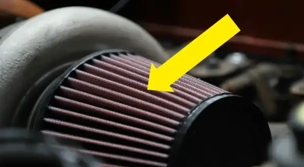 En gul pil pekar på det röda luftfiltermaterialet på ett bilfilter.