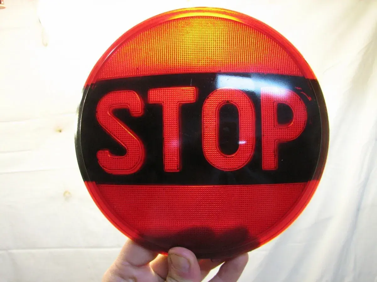 Rött stoppskylt med texten "STOP" i svarta bokstäver. En klassisk olja symbol för att stanna.