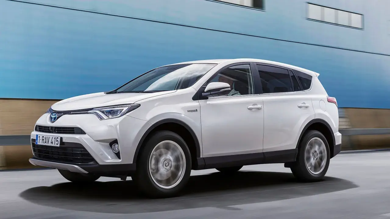 Vit Toyota RAV4 Hybrid körs på vägen, kanske med ett **toyota rav4 automat problem** som behöver åtgärdas.