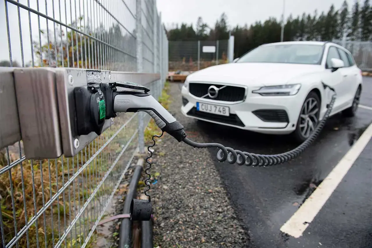 En vit Volvo laddas vid en laddstation. Perfekt för att hitta laddstationer när du är på språng.